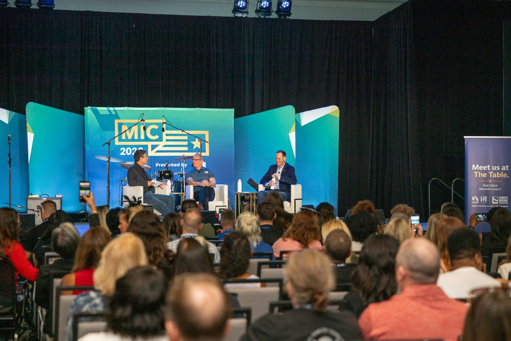 A panel conversation on the main stage at the Military Influencer Conference, seen over a full audience
